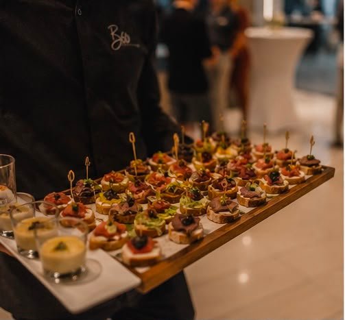Servicekraft trägt ein Tablett mit Fingerfood-Häppchen